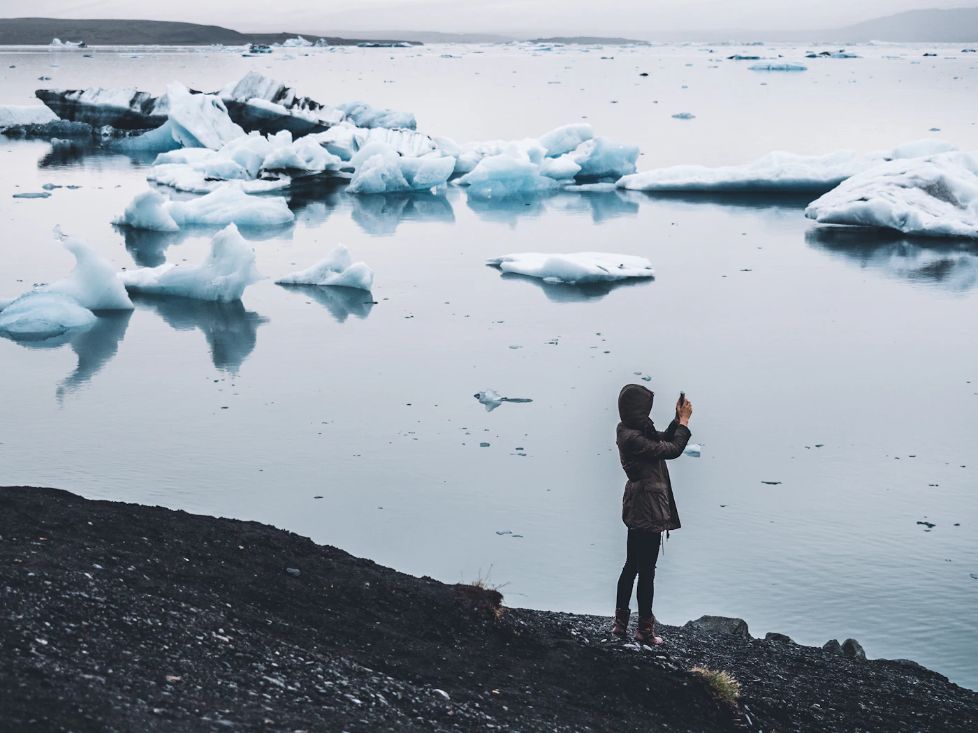 A person photographing ice floes on the lagoon