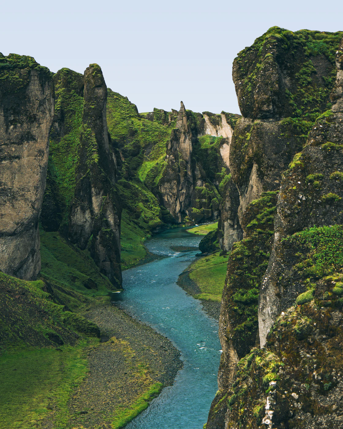 A turquoise river winding through the mossy Fjaðrárgljúfur canyon