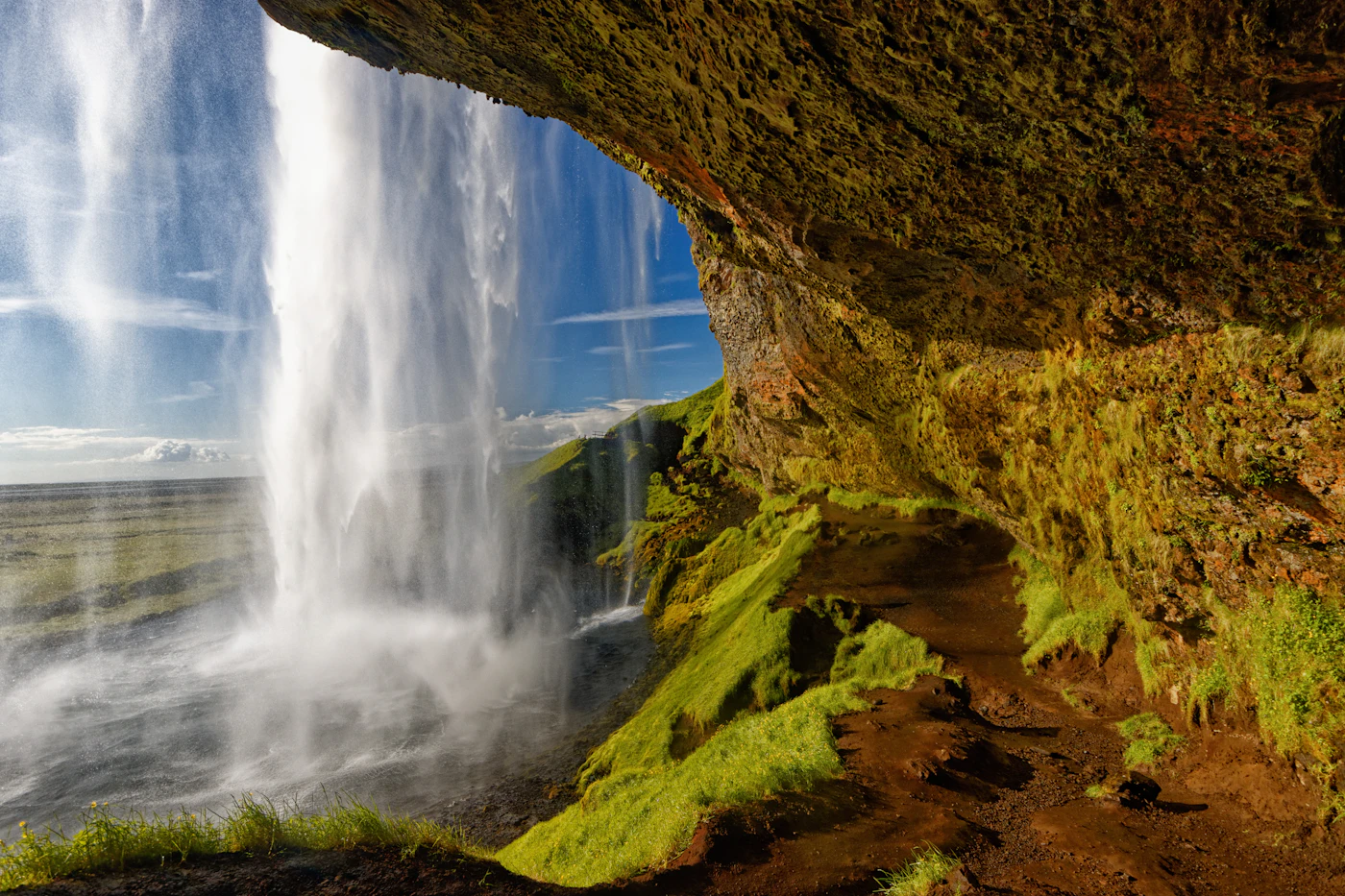 Water pouring past a mossy overhang behind Seljalandsfoss