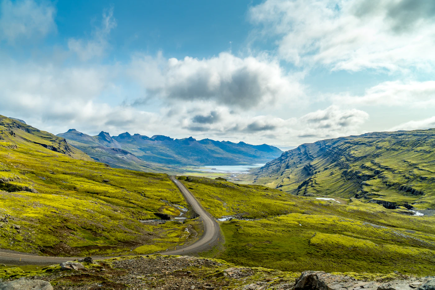 A road winding through bright green hills toward the sea