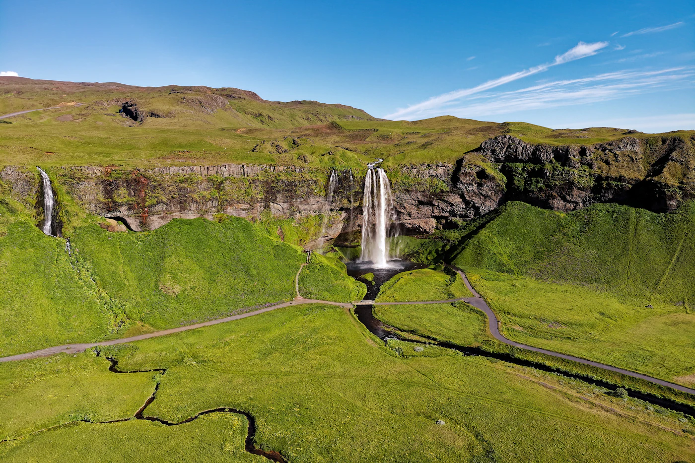 Seljalandsfoss from a distance across green farmland