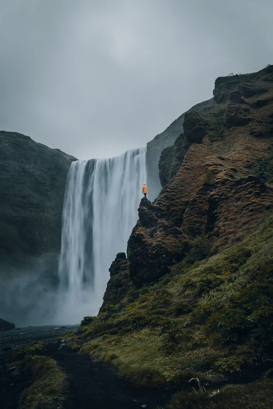 A hiker on the ridge beside Skógafoss